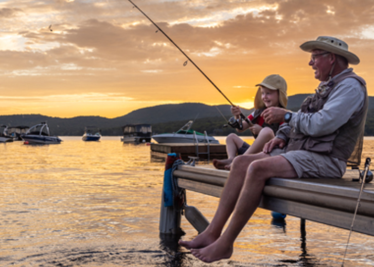 grandad and kid fishing in the sunset